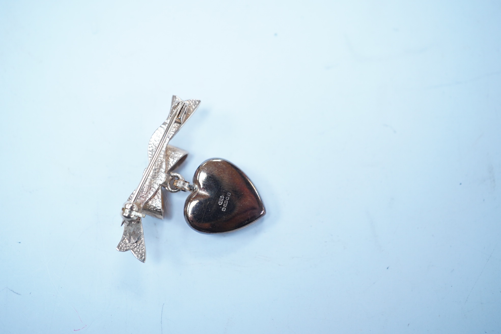 A modern engraved 9ct gold heart shaped locket, on an associated 9ct gold ribbon bow suspension brooch, width 31mm, gross weight 4.2 grams. Condition - fair to good